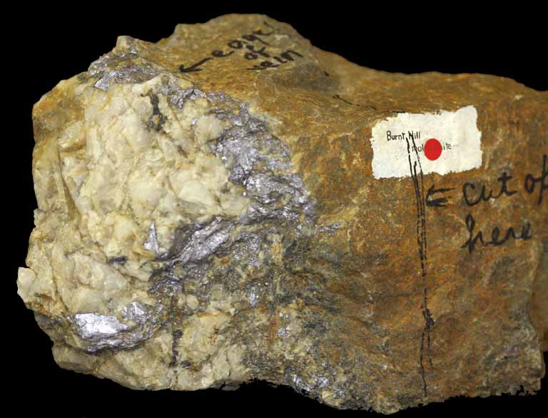 Colour image of brown rock with large sections of white and gray metallic rock