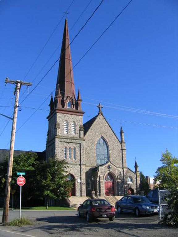 Photographie couleur d’une église en pierre dotée d’un grand clocher sur la gauche