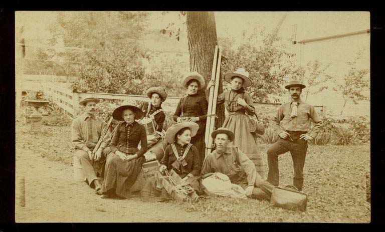 Black and white photograph of five women and three men in front of a tree