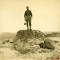 Black and white photograph of man standing on a large boulder